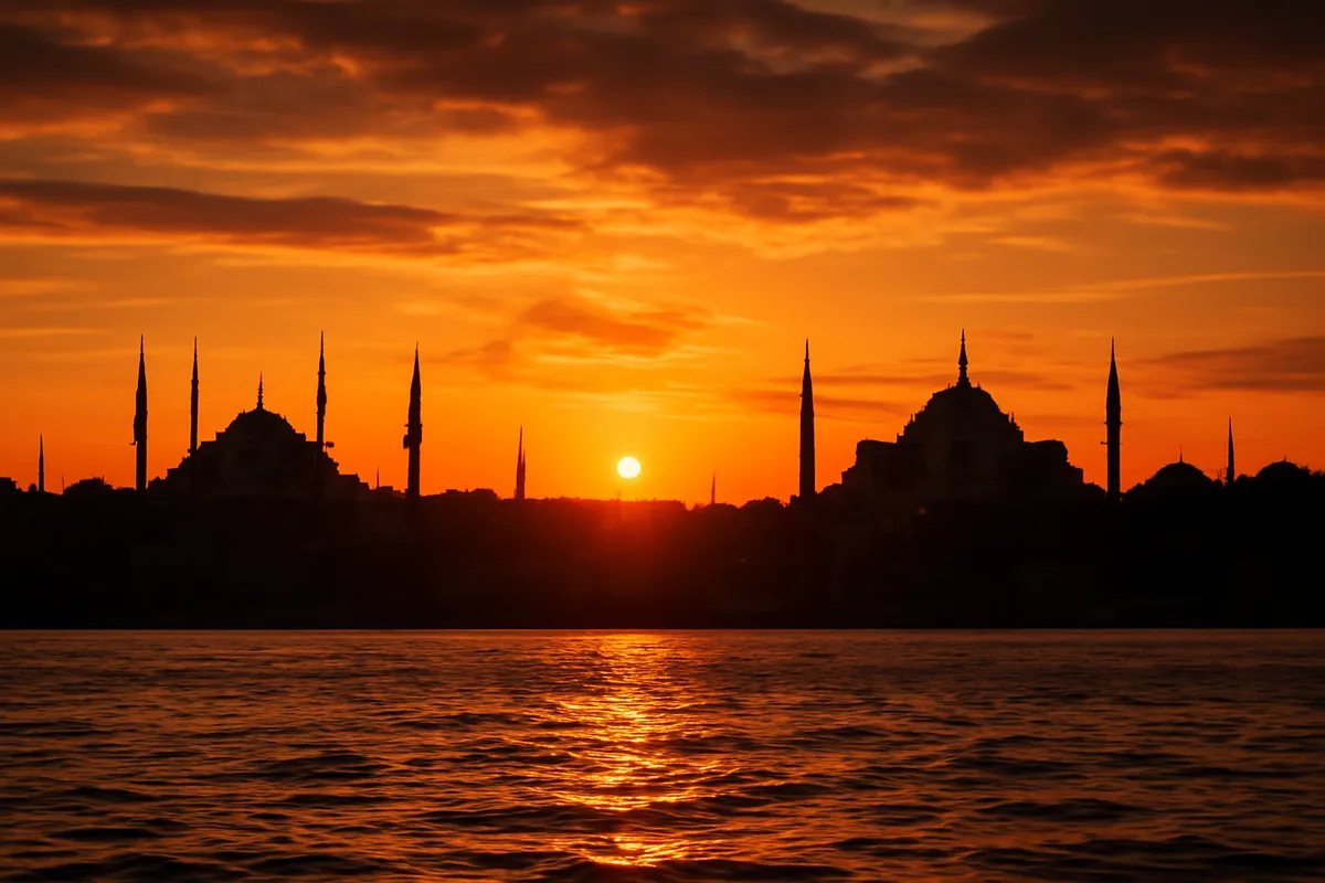 Panoramic sunset view of Istanbul skyline with historic mosque silhouettes and minarets reflected in the golden waters of the Bosphorus strait