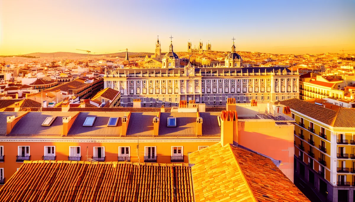 Panoramic view of Madrid's historic cityscape featuring the Royal Palace and cathedral spires during golden hour