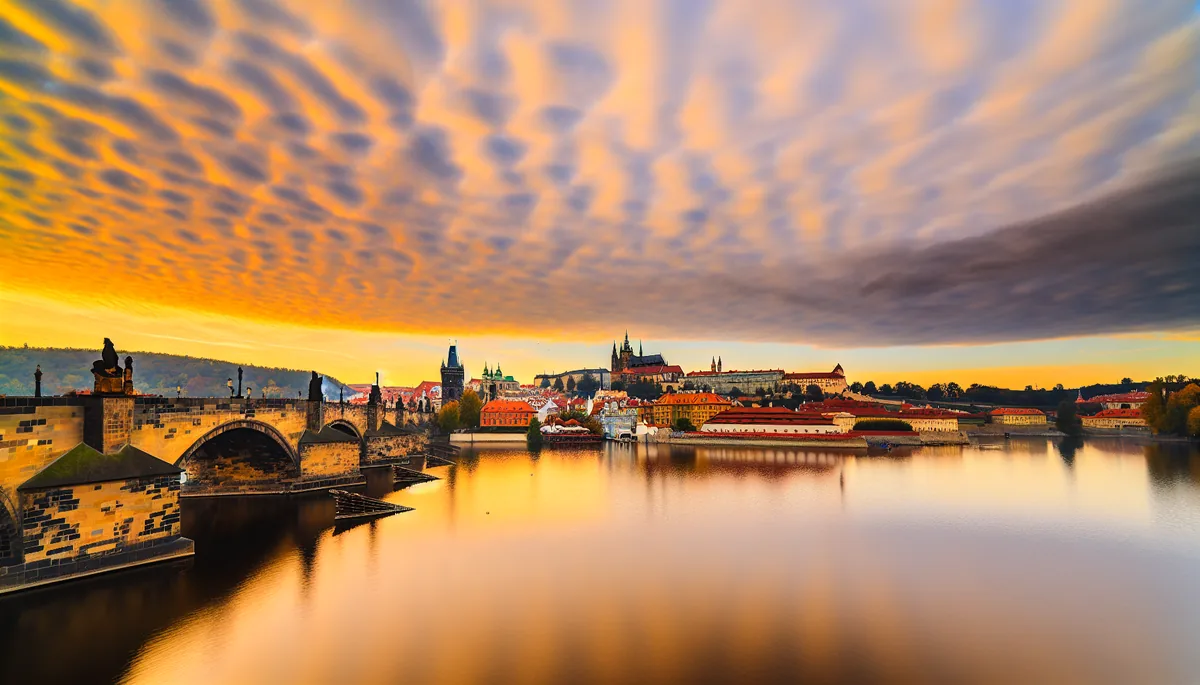 Golden hour view of Prague Castle and Charles Bridge over the Vltava River with historic Czech architecture