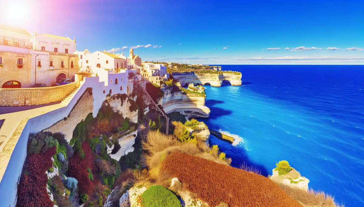 Breathtaking Mediterranean coastal landscape with traditional European architecture overlooking crystal blue waters under bright spring sunshine