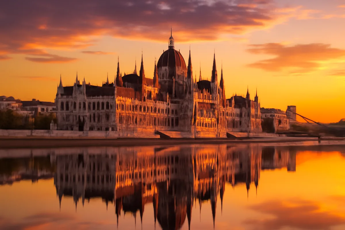 The Hungarian Parliament Building and Chain Bridge reflected in the Danube River during a golden sunset in Budapest