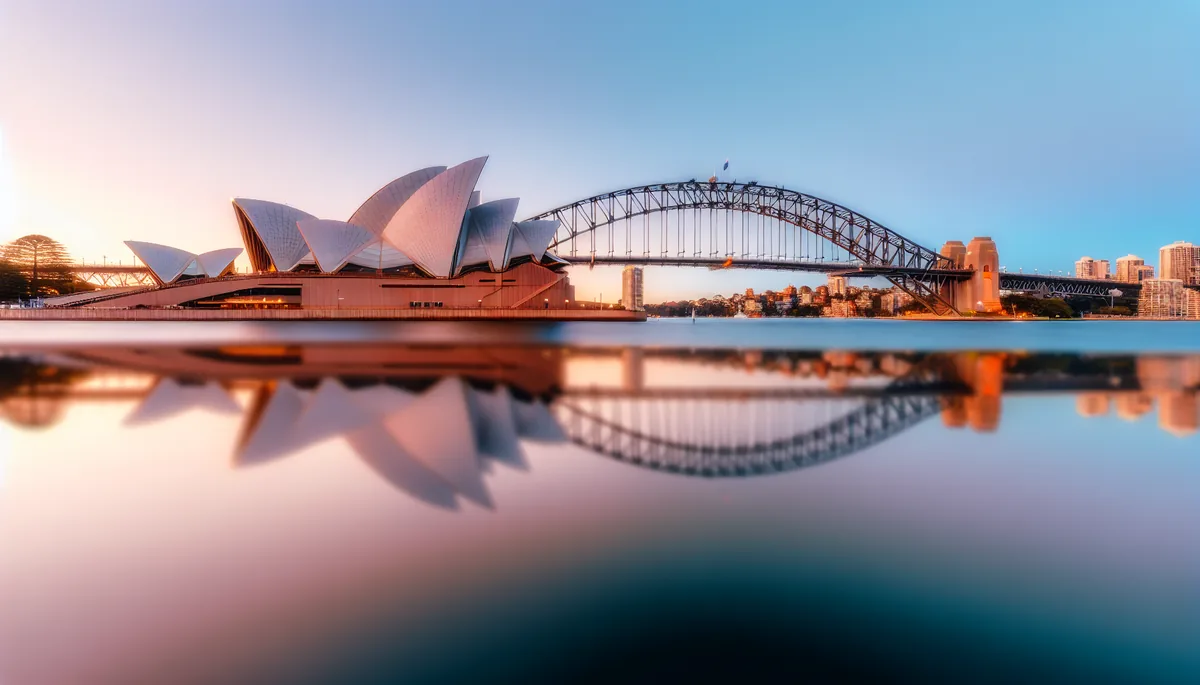Sydney Opera House and Harbour Bridge at sunset with golden reflections in the harbor water