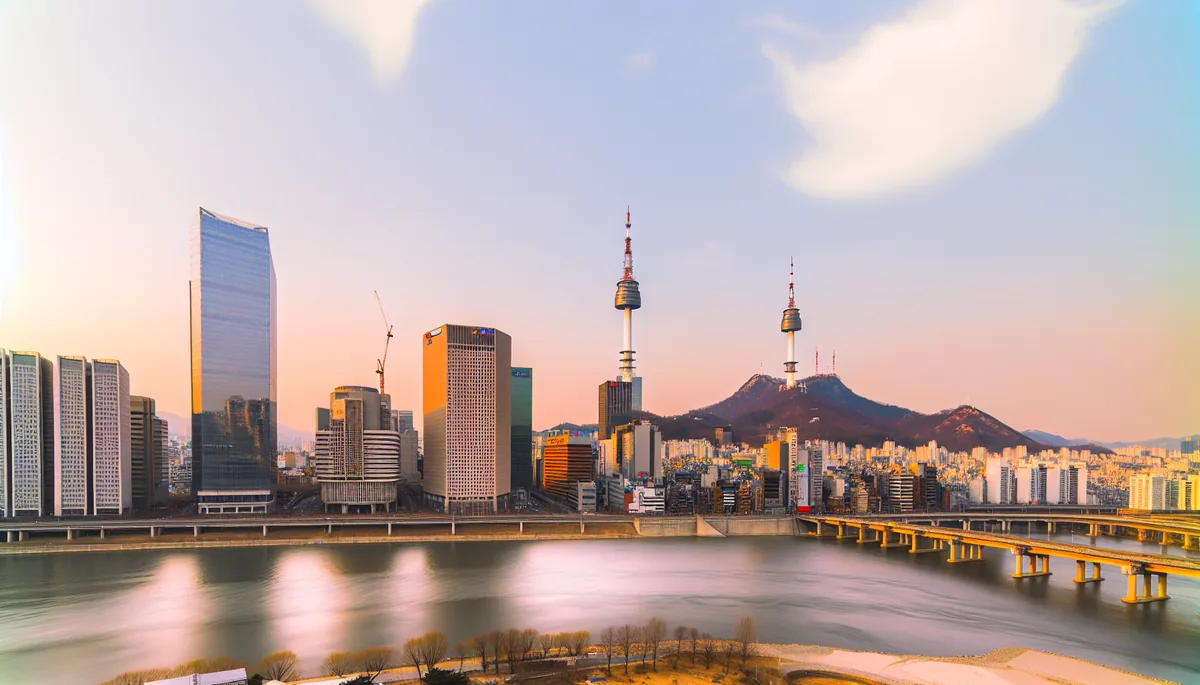 Panoramic view of Seoul skyline featuring Namsan Tower and modern buildings along the Han River during golden hour