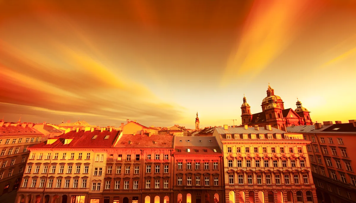 European city skyline at sunset with historic and modern architecture bathed in golden light