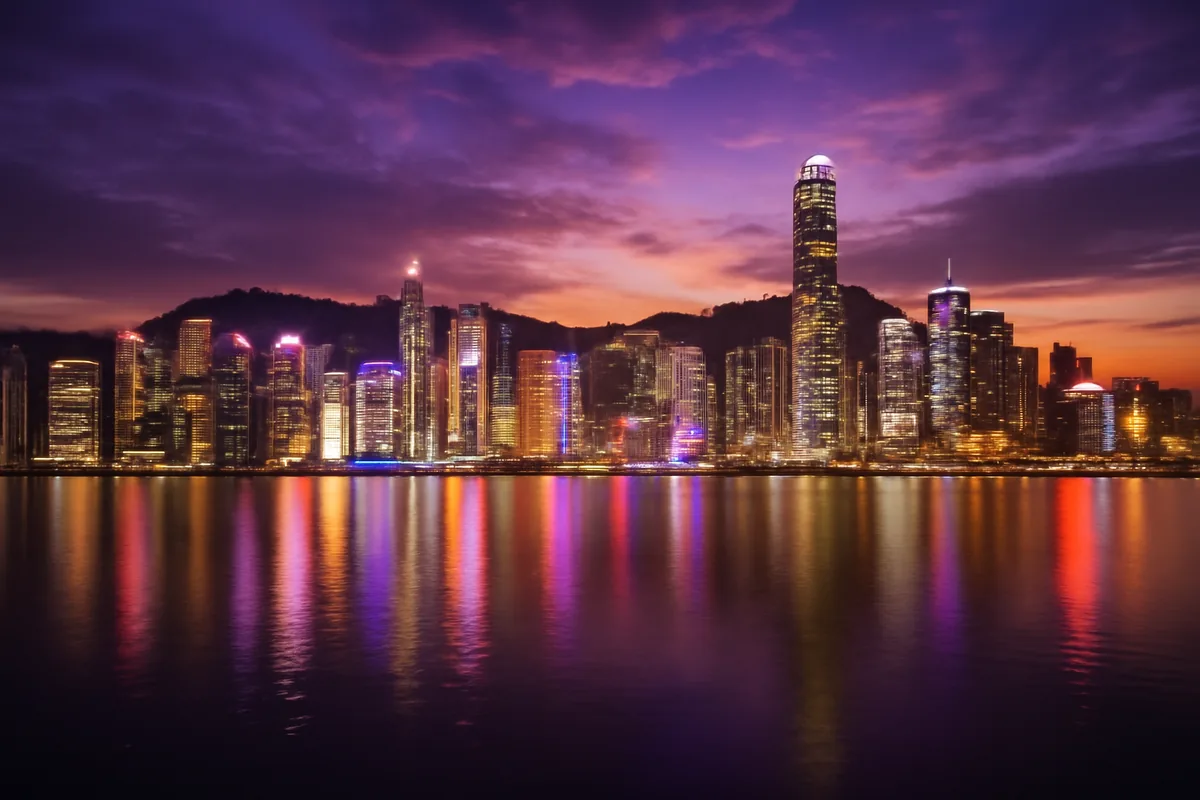 Hong Kong skyline at twilight with Victoria Harbour reflecting the glittering lights of skyscrapers under a dramatic purple and golden sky