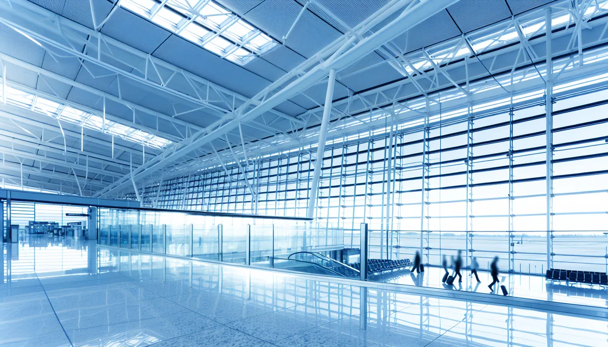 Modern airport terminal interior with geometric glass architecture and travelers walking through bright corridors