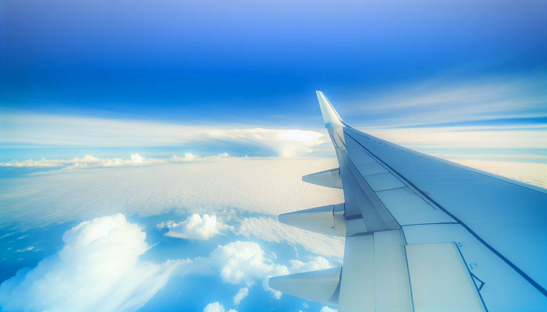 View from airplane window showing aircraft wing with clouds below and blue sky above during flight