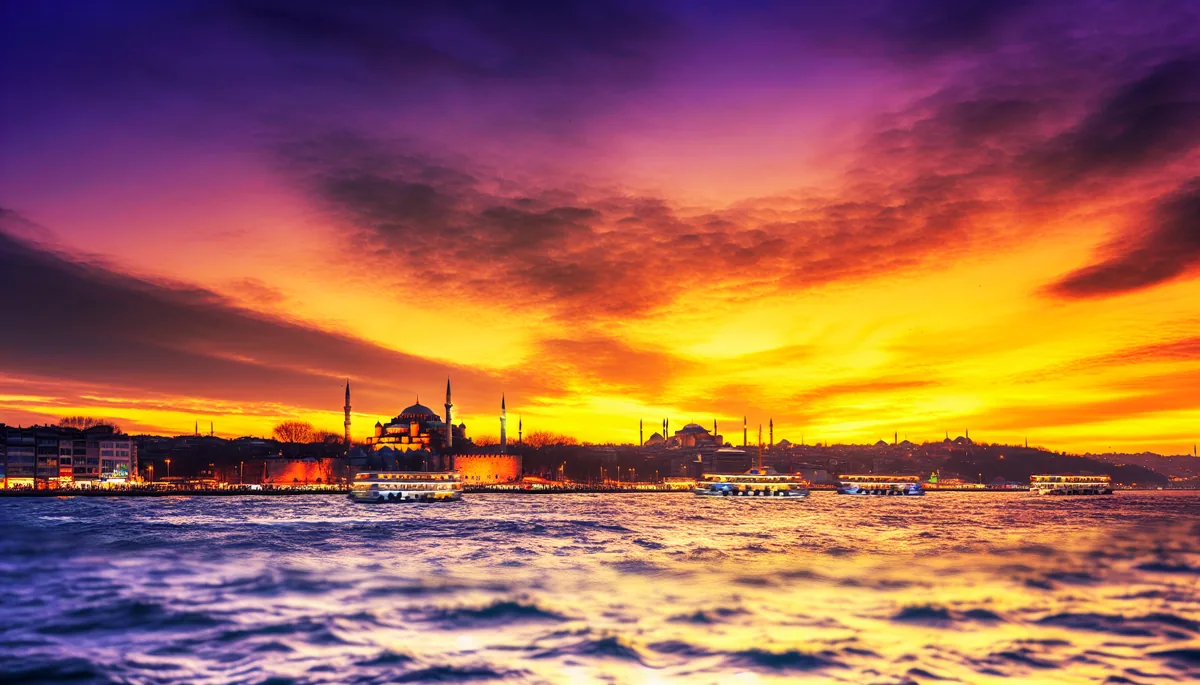 Stunning sunset view of Istanbul's historic skyline featuring the Blue Mosque and Hagia Sophia with the Bosphorus strait and traditional boats in the foreground